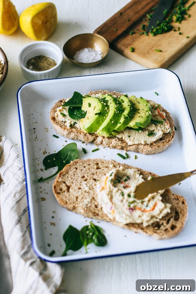 veggie cream cheese on toast with avocado spinach on white tray with lemons, salt, and pepper