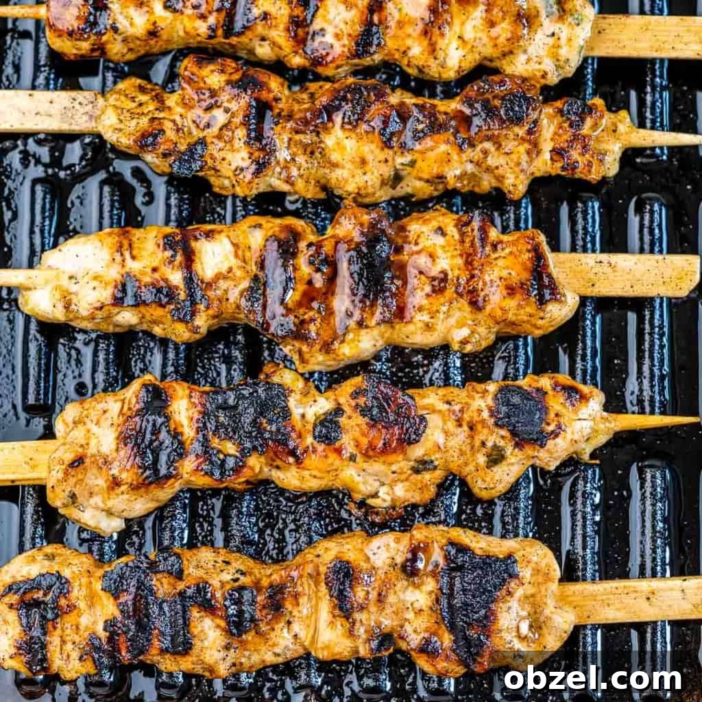 Grilled Lemon Chicken Skewers with Garlic and Herbs 6 grilled lemon chicken skewers on grill with marinade