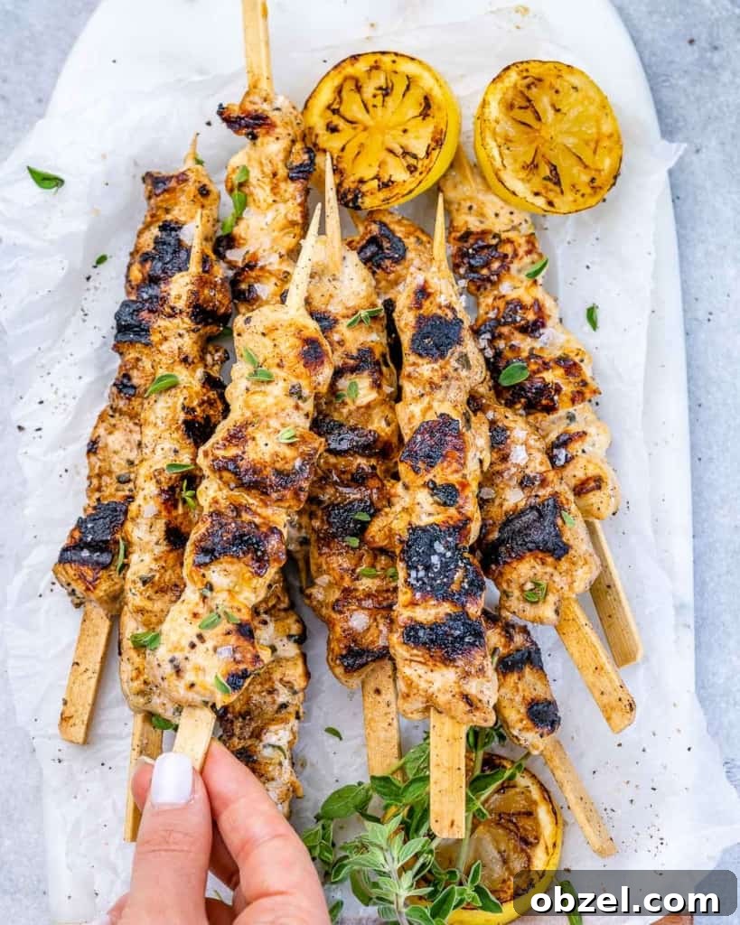 Grilled Lemon Chicken Skewers with Garlic and Herbs 8 grilled lemon chicken skewers on top of white surface