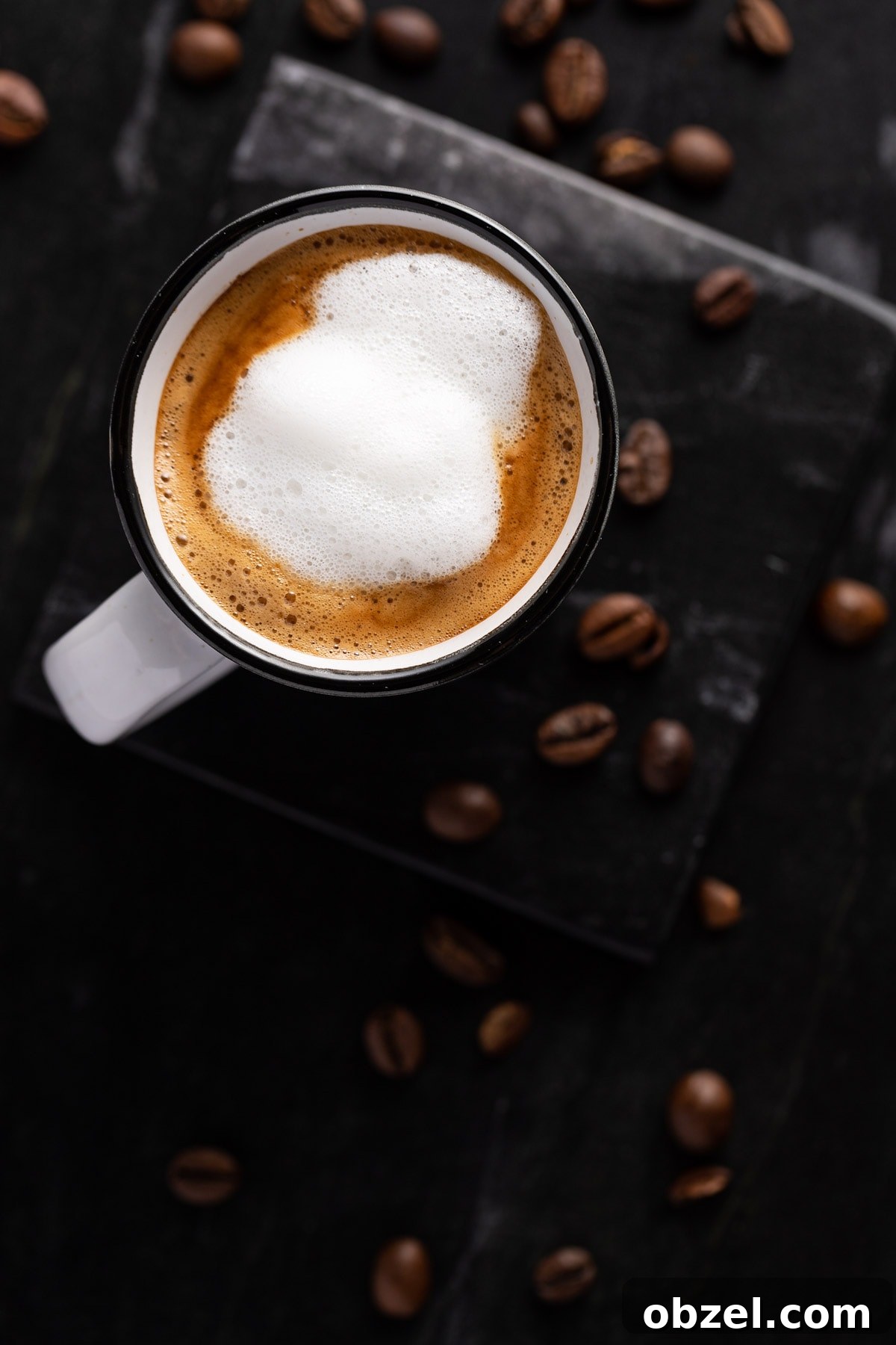 Starbucks Doppio Caffeine Calories and Price 6 Overhead view of a starbucks doppio with foamed milk on top, in a white espresso cup, on a black marble table.