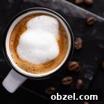 Overhead view of a starbucks doppio with foamed milk on top, in a white espresso cup, on a black marble table.
