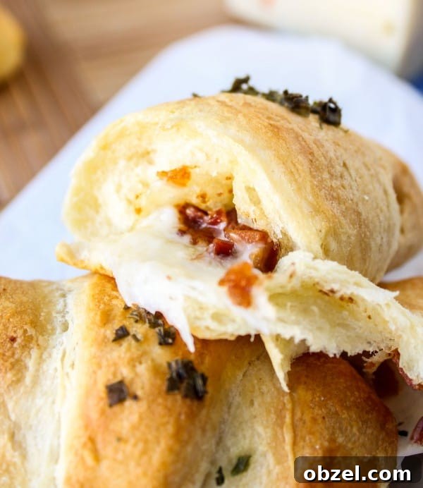 Cheesy Bacon and Pepper Jack Stuffed Crescent Rolls 12 two stuffed crescent rolls, one cut in half with bacon and cheese oozing from it.