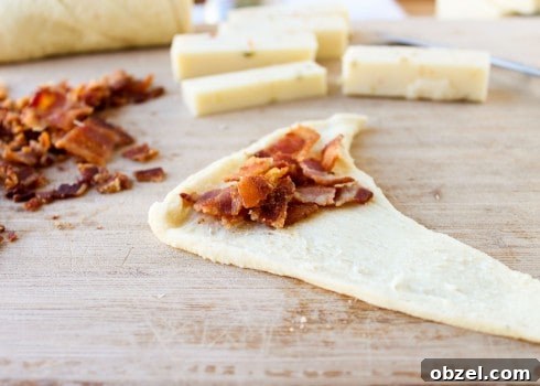 Cheesy Bacon and Pepper Jack Stuffed Crescent Rolls 7 Bacon on an unbaked crescent roll on a cutting board.