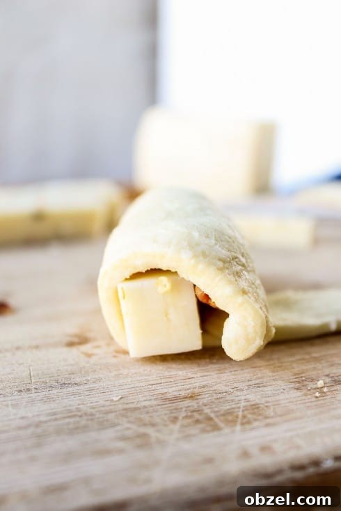 Cheesy Bacon and Pepper Jack Stuffed Crescent Rolls 10 wrapping a bacon and cheese crescent roll on a cutting board.