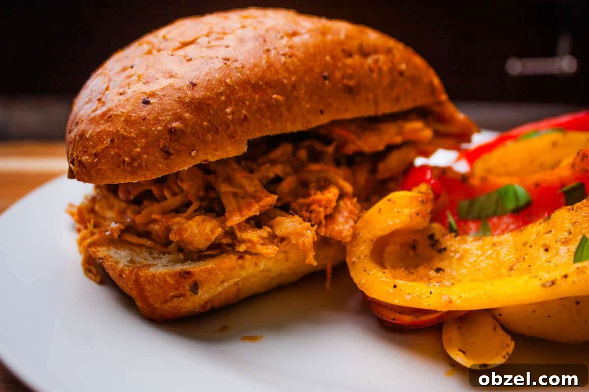 Smoked Pulled Pork Loin on a Traeger Grill 6 The shredded pork loin on a bun with a side of smoked peppers.