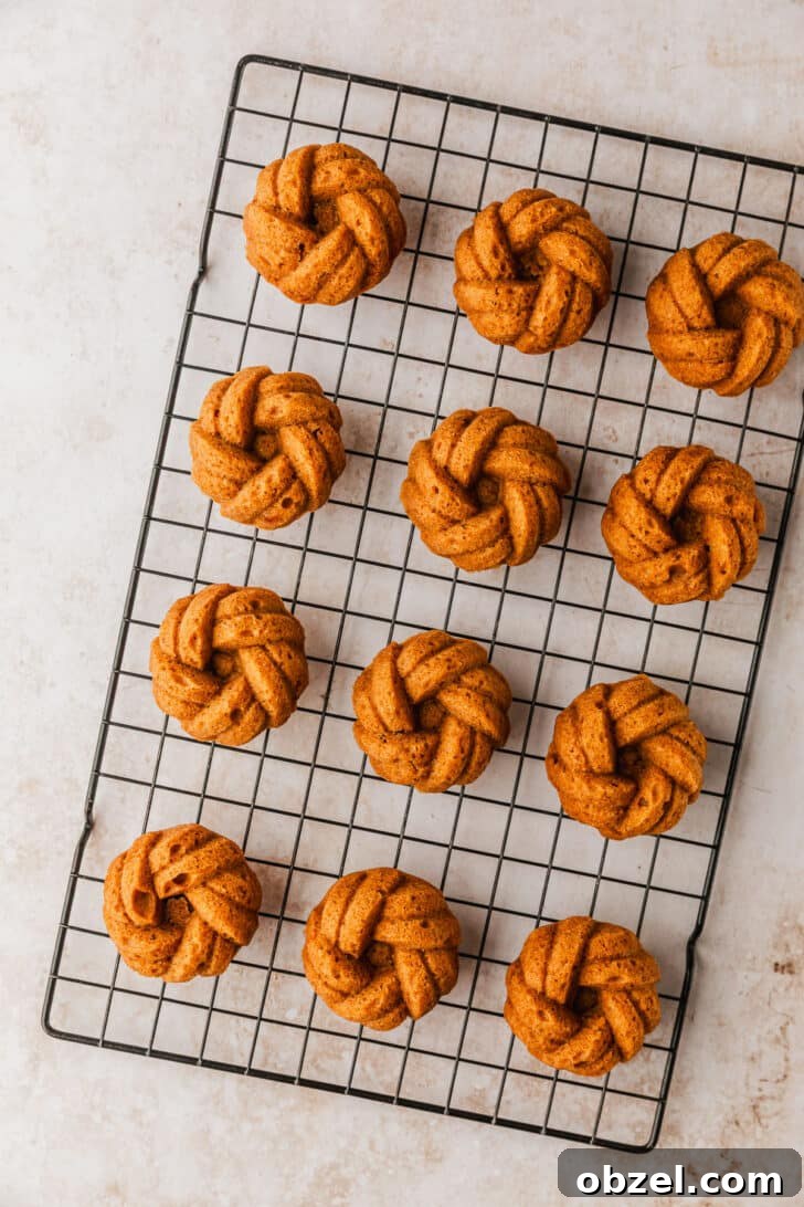Pumpkin Spice Mini Bundt Cakes 10 A wire rack of pumpkin mini bundt cakes on a beige marble counter.