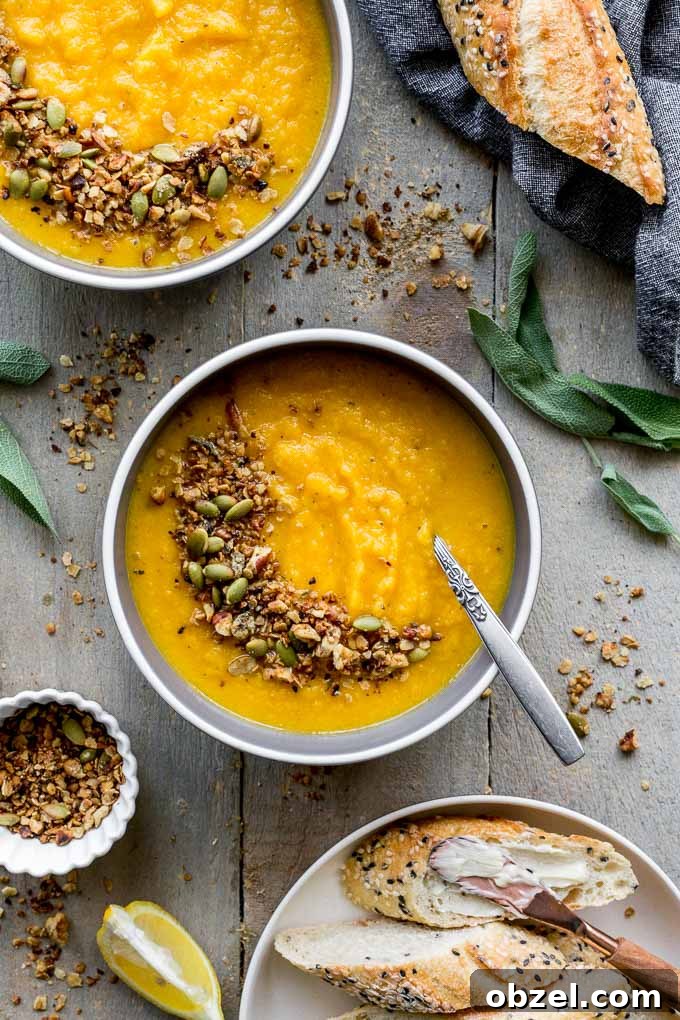 Vegan Golden Beet Soup with Carrot and Ginger 6 Overhead view of two bowls of golden beet soup with granola sprinkled on top and bread off to the side.