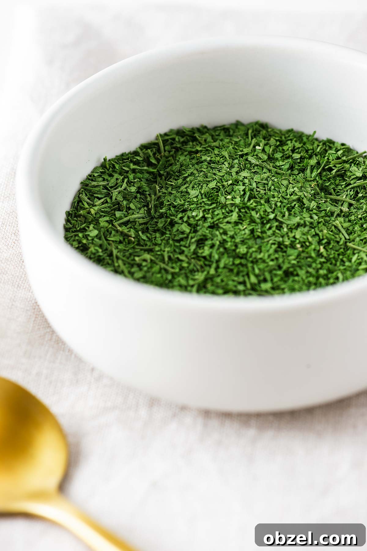 How to Dry Parsley in the Oven for Crisp, Flavorful Herbs 2 A small white ceramic bowl with oven dried parsley.