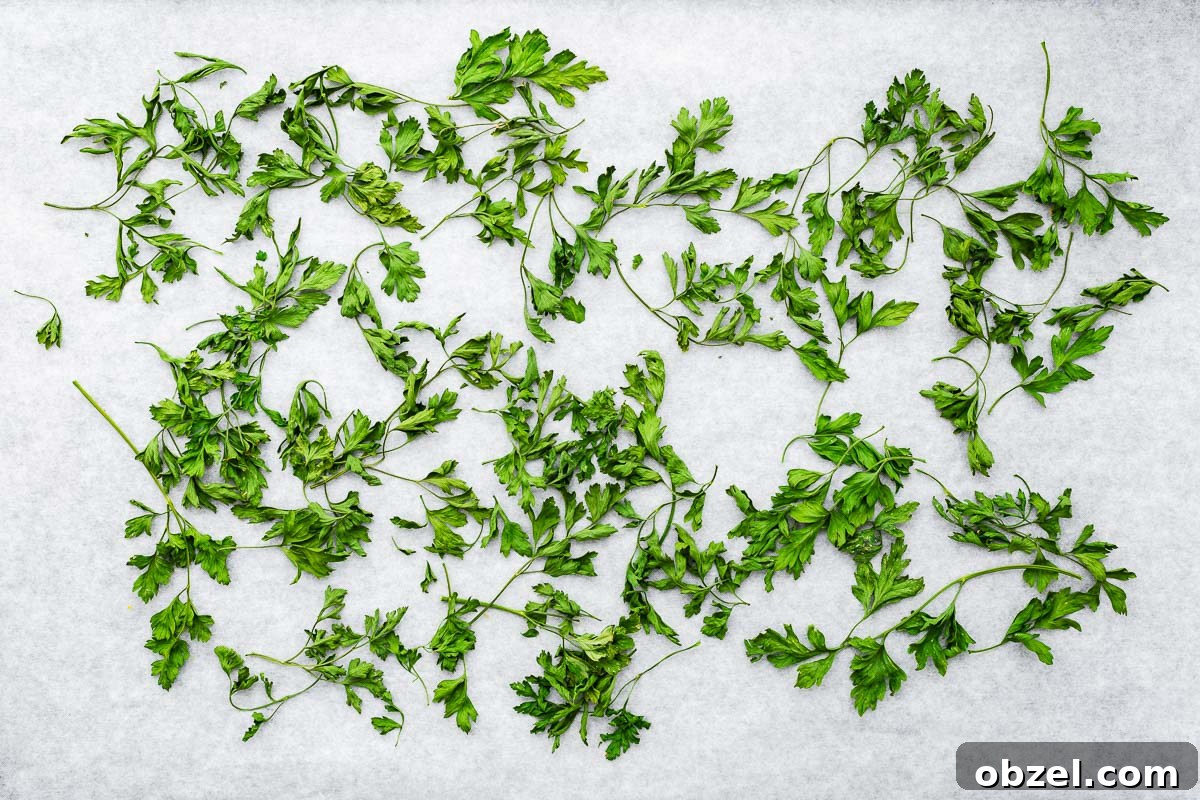 How to Dry Parsley in the Oven for Crisp, Flavorful Herbs 6 Oven dried parsley leaves and stems on parchment paper viewed from above.