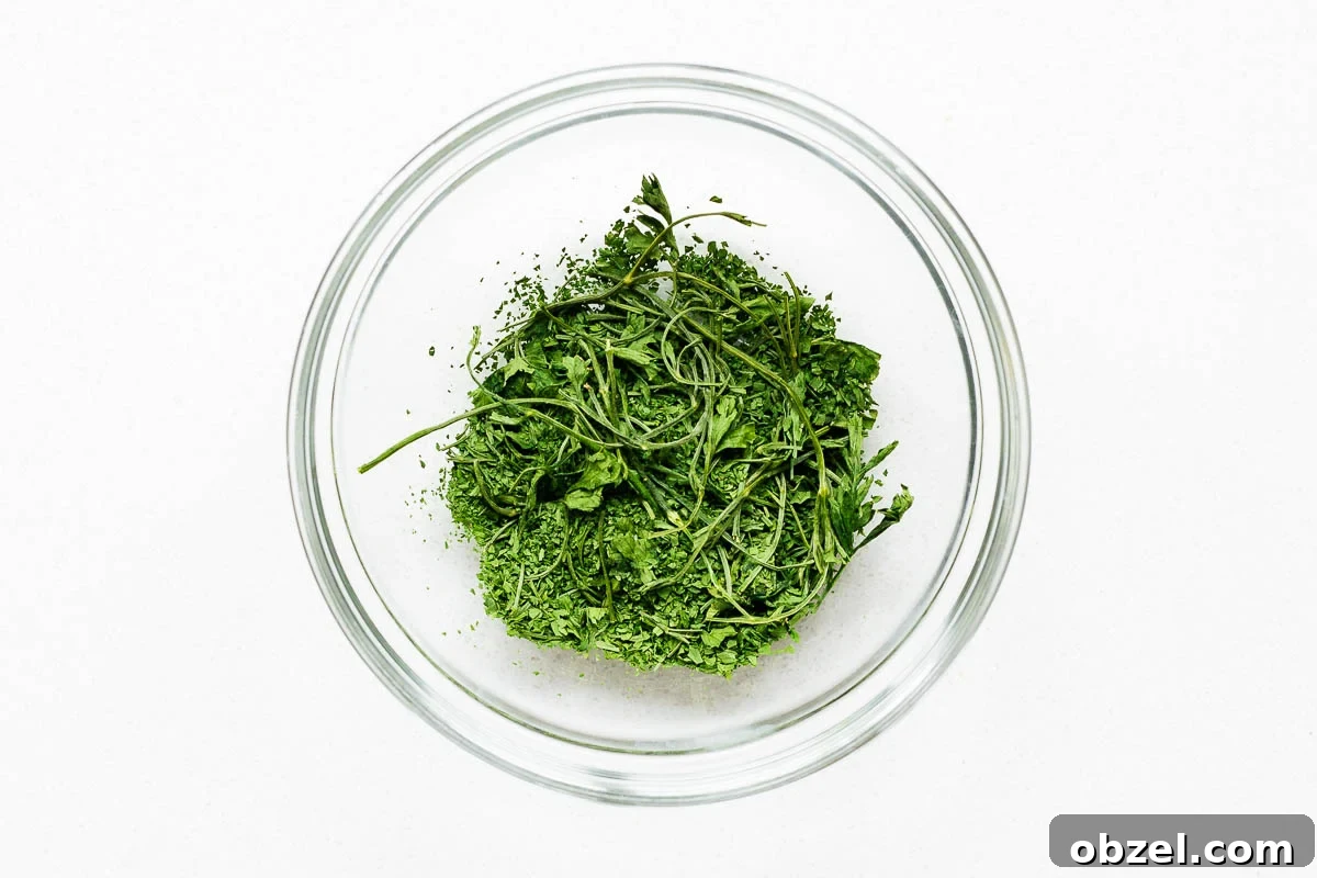 How to Dry Parsley in the Oven for Crisp, Flavorful Herbs 7 Roughly crumbled oven dried parsley with stems in a glass bowl.
