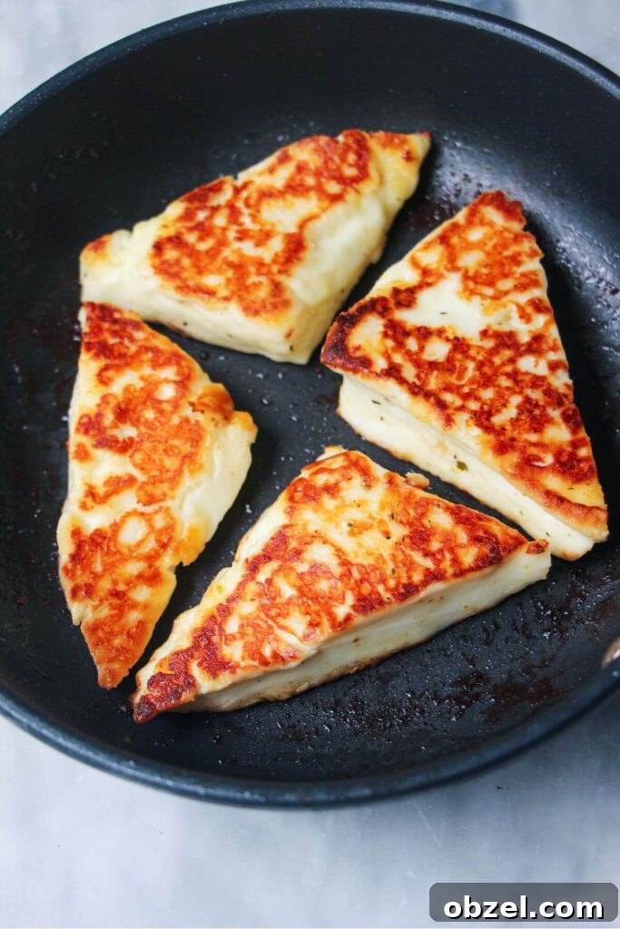 Honey and Harissa Glazed Halloumi Recipe 8 4 wedges of golden pan fried halloumi in a small black pan.