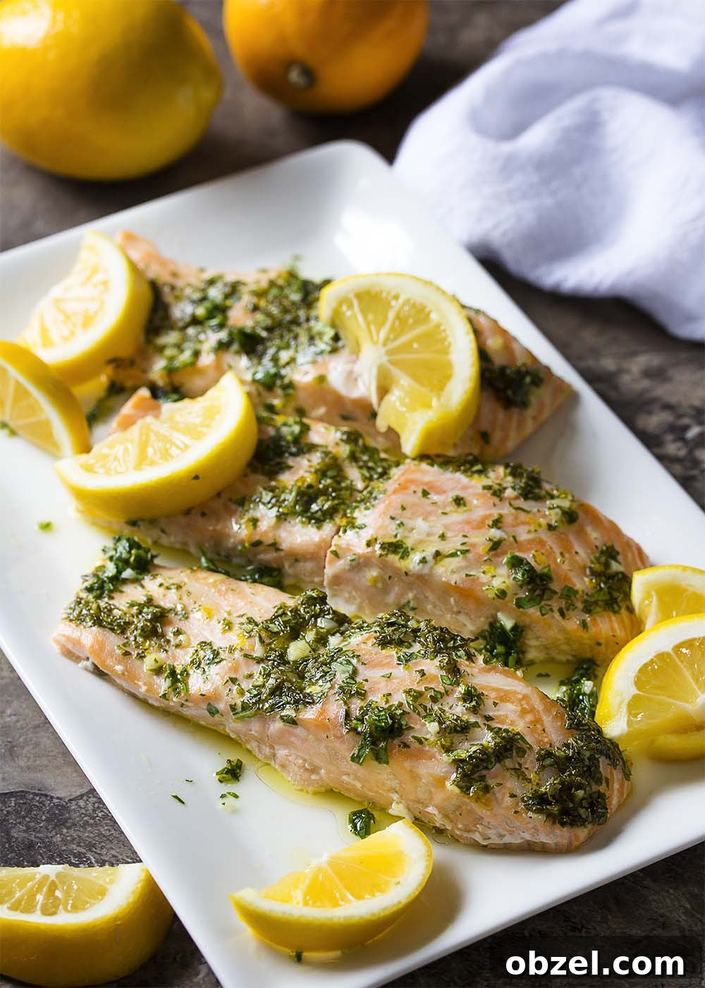 Tender slow roasted salmon served with lemon herb sauce. A plate of slow roasted salmon fillets topped with a lemon herb sauce.