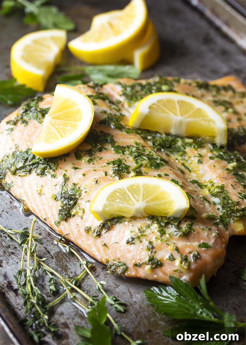 Tender slow roasted salmon with lemon and herbs. Tender salmon on a baking sheet right out of the oven with lemon and herbs.