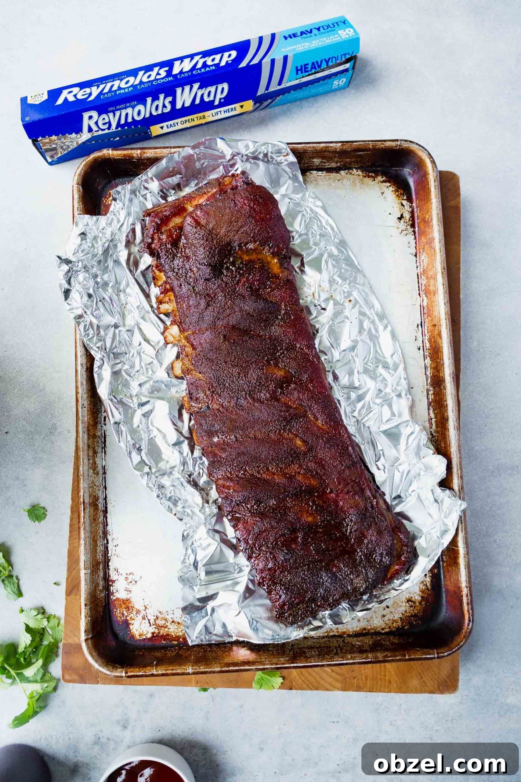 Easy BBQ Spare Ribs a photo of a grilled rack of ribs sitting on a sheet of foil on top of a baking sheet
