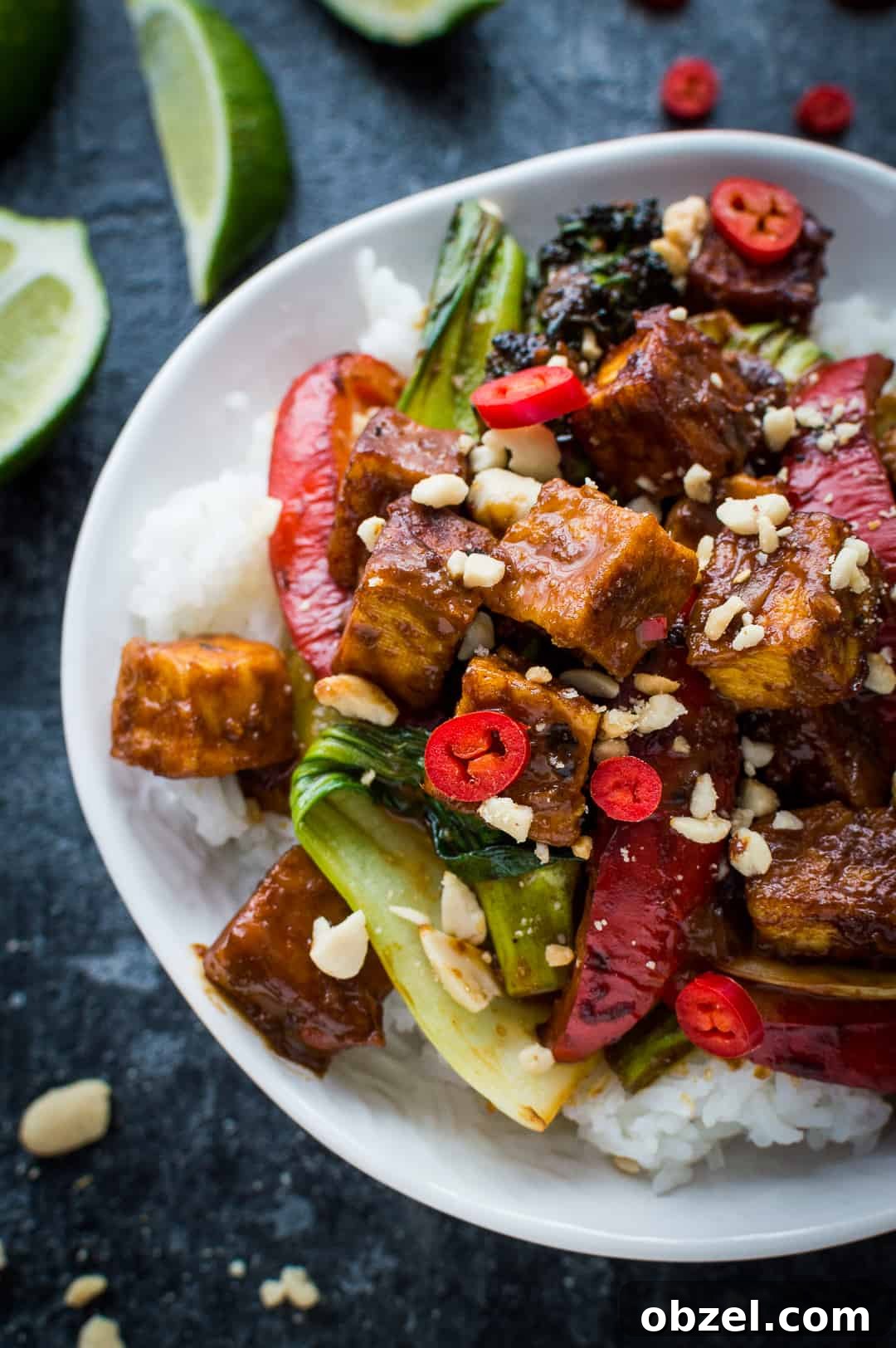 Peanut tofu stir fry served on a bed of rice on a white plate