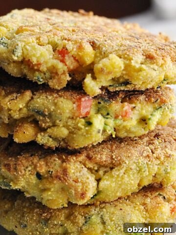 Four corn zucchini fritters with red peppers stacked on plate.
