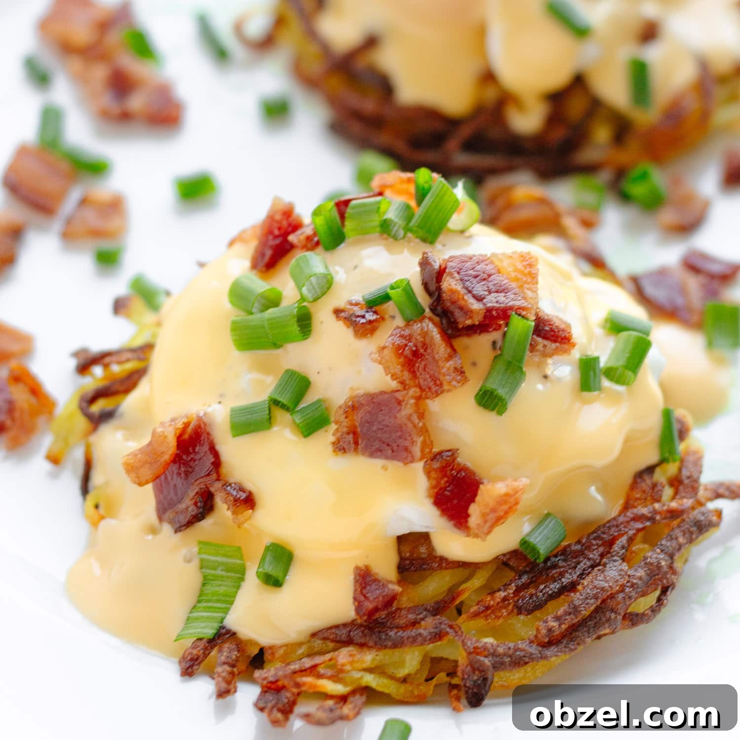 Rosti Eggs Benedict with Crispy Potato Pancakes 7 Closeup of eggs Benedict on a potato rosti garnished with chopped bacon and chives.