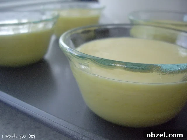 A close up of small glass dishes on a baking sheet with batter in each dish.
