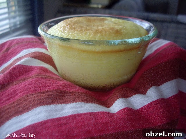 A close up of a baked mini cake in a small glass dish on top of a dish towel.