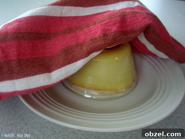 A plate with an upside down glass dessert cup on it with a dish towel on top.