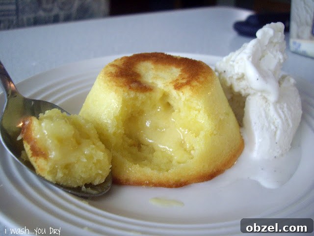 A spoon displaying the liquid center of a mini cake on a plate next to a scoop of ice cream.