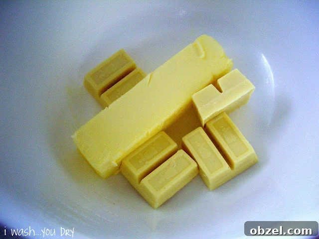 A stick of butter and four squares of white baking chocolate in a dish.