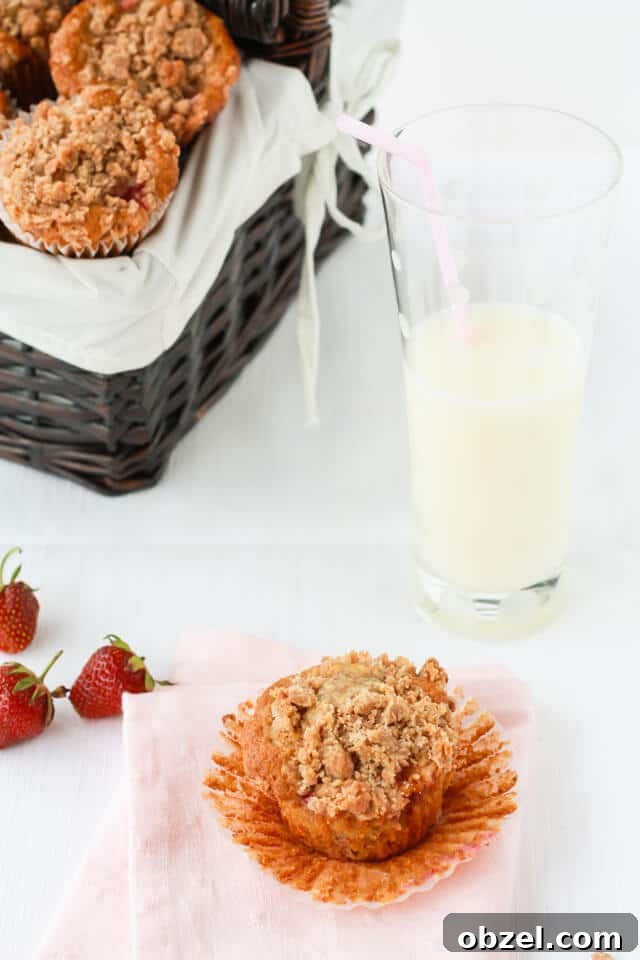 Strawberry rhubarb muffins with streusel crumbled on top served in a basket with a glass of milk