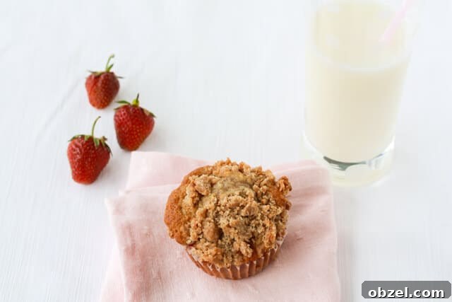 Strawberry rhubarb muffins with streusel crumbled on top served in a basket with a glass of milk