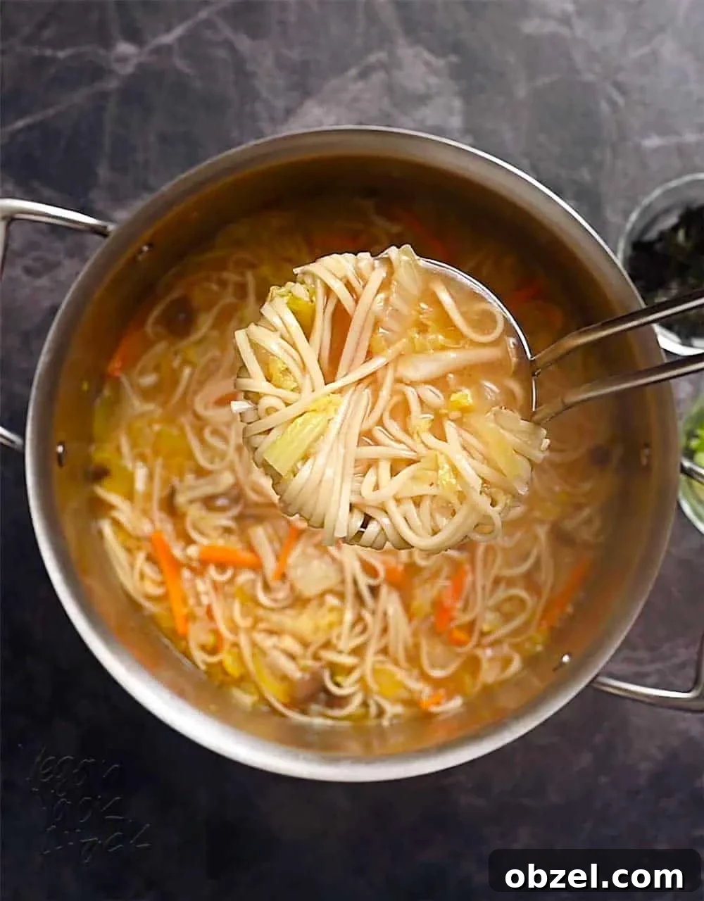 Spicy Vegan Udon Noodle Soup Recipe 6 Scooping noodle soup out of a large pot with a ladle