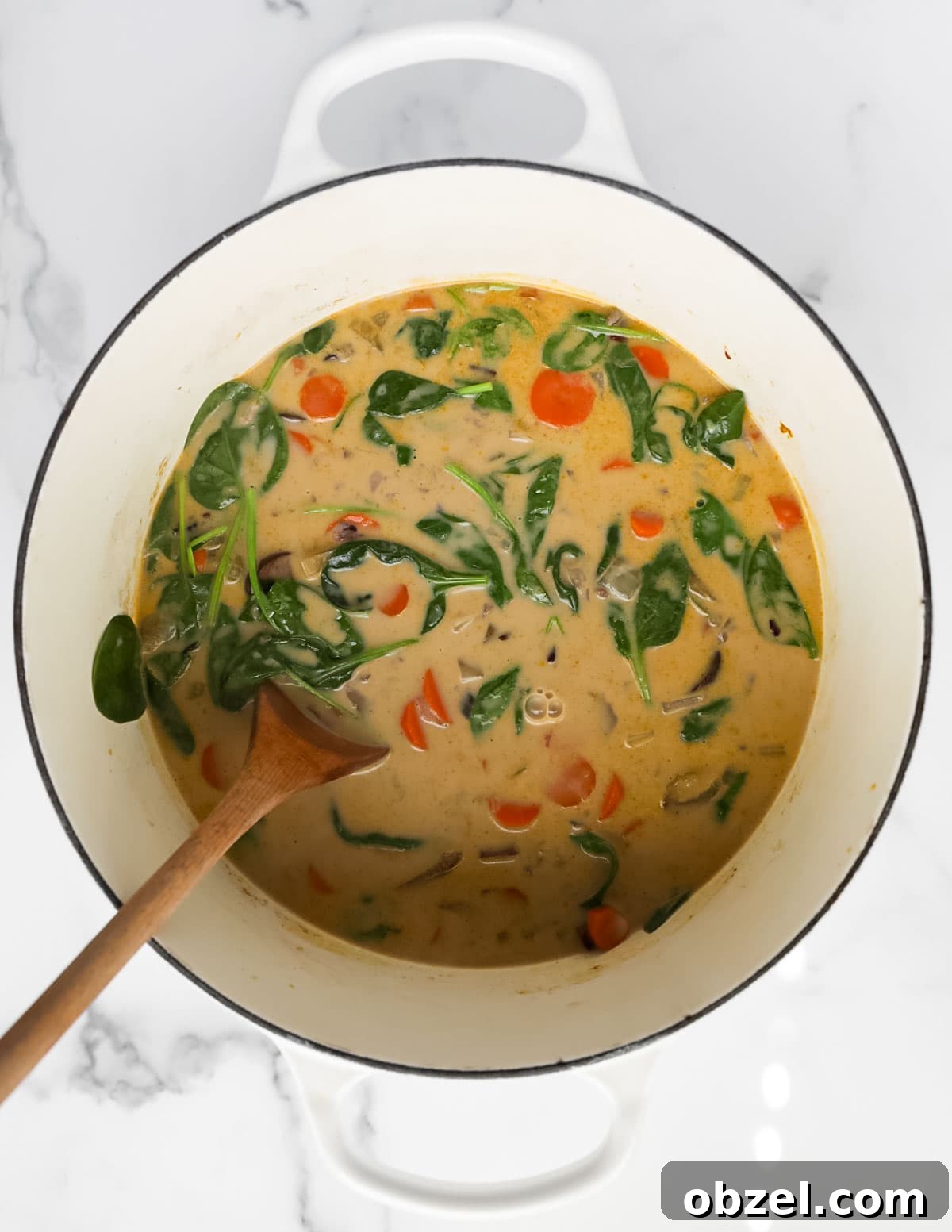 Creamy Wild Rice and Mushroom Soup Recipe 7 A white pot filled with creamy vegetable soup.