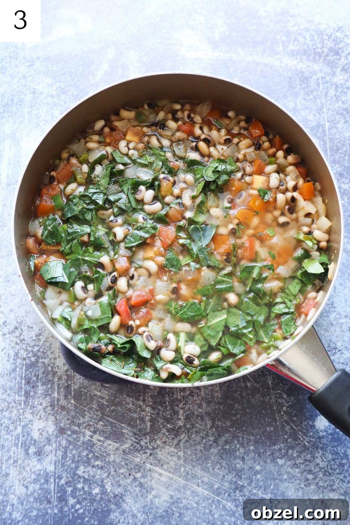 skillet with black eyed peas, chicken broth, collards, tomatoes, garlic, and onion.