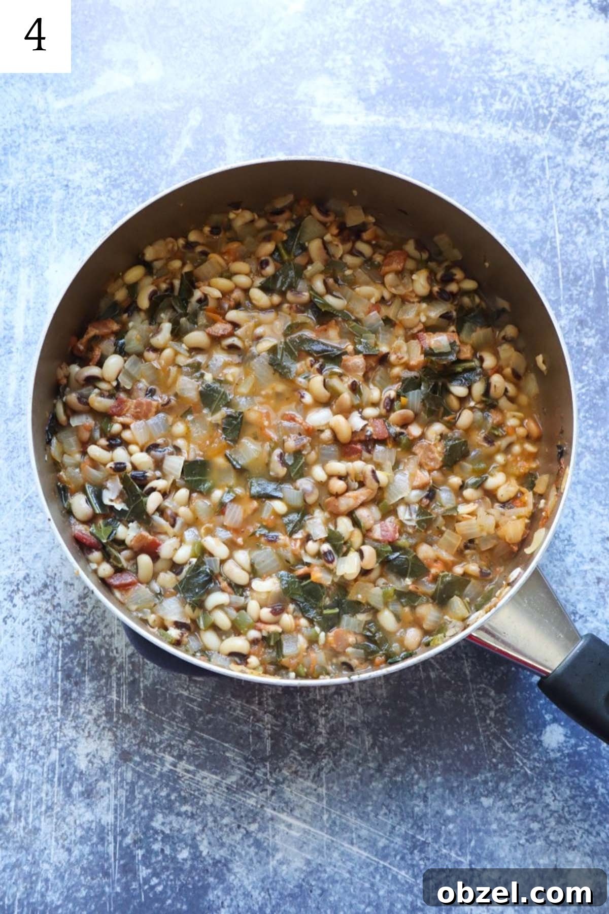 skillet with cooked black eyed peas with collards, jalapenos, and tomatoes.