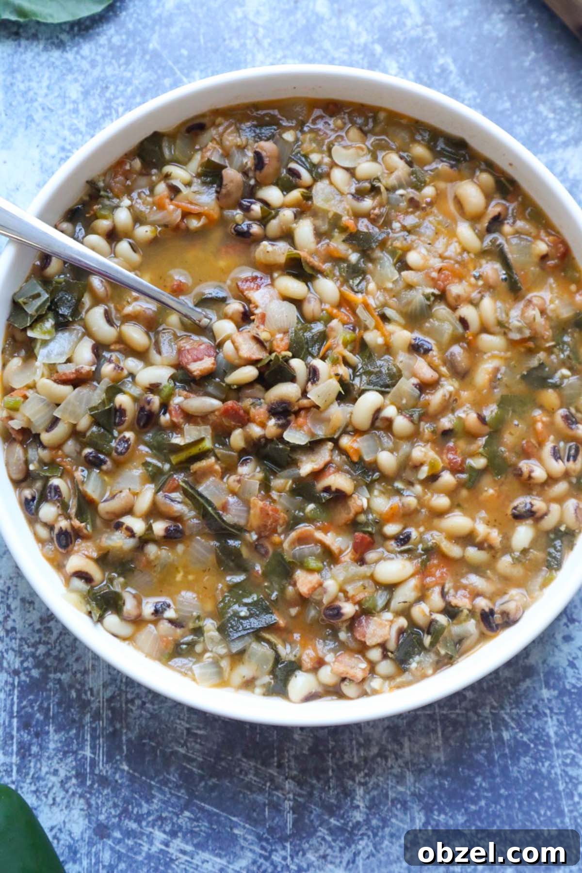 white bowl with cooked black eyed peas with bacon and collards.