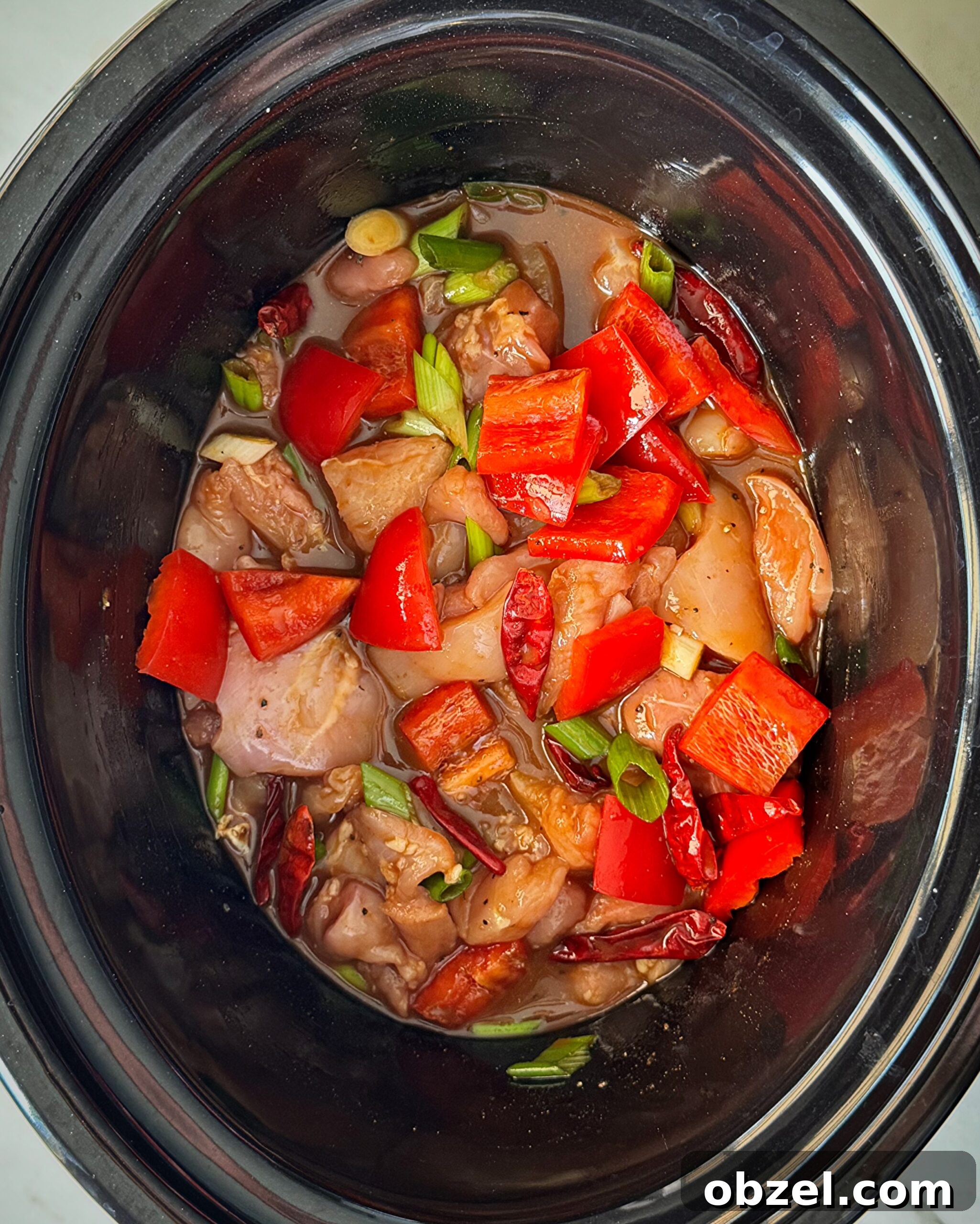 overhead shot of uncooked Kung Pao Chicken (Panda Express Copycat) in a black slow cooker