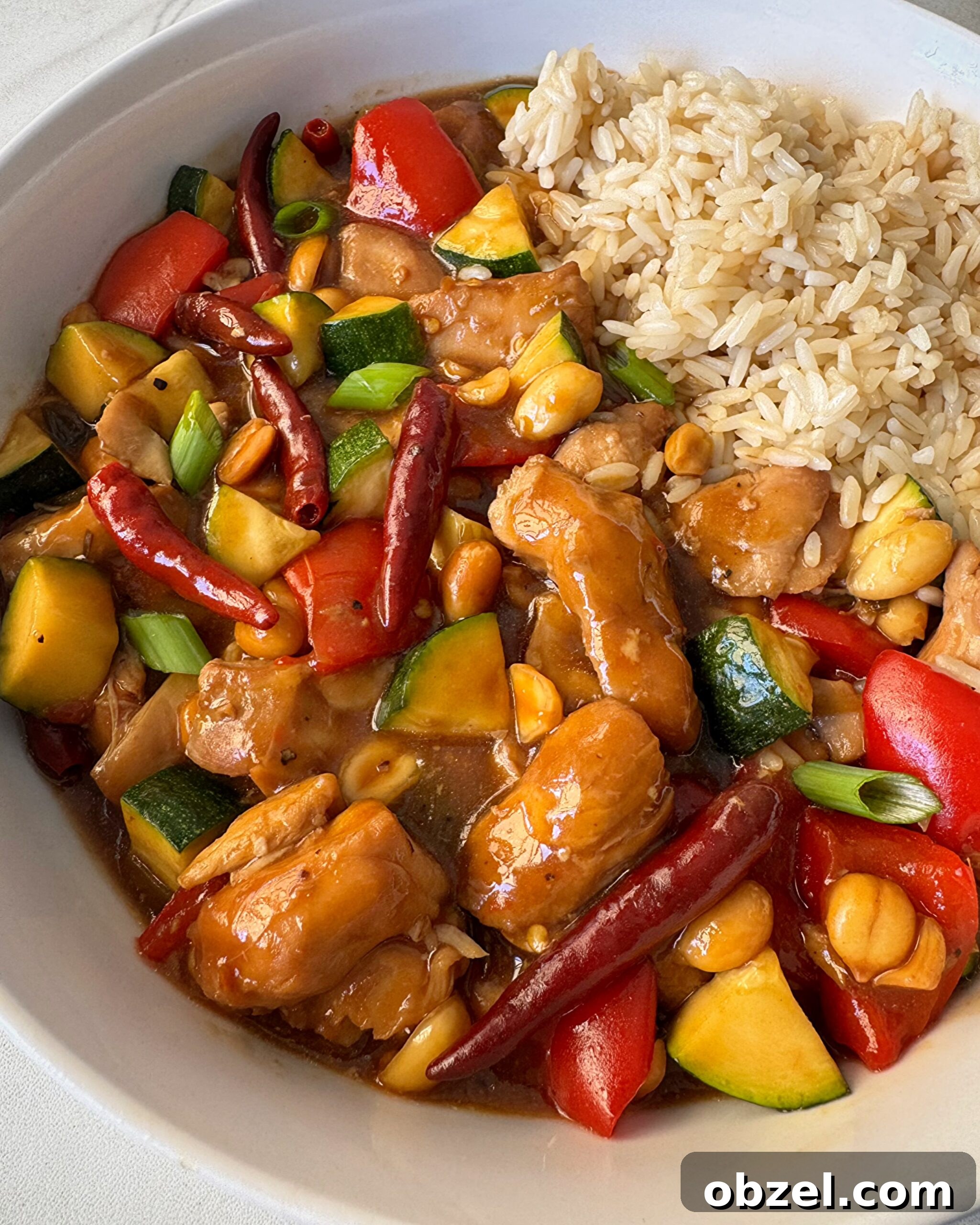 close up shot of cooked Kung Pao Chicken (Panda Express Copycat) on a white plate with white rice