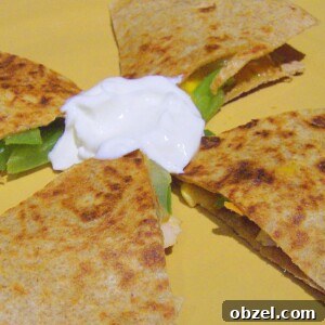 A grilled veggie quesadilla cut into quarters with vegan sour cream in the center on a yellow plate