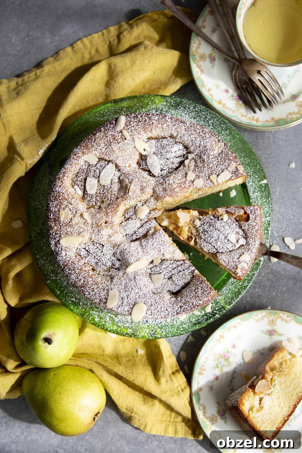 Pear Almond Cake served on a platter with sliced pears baked into the top Arial view of a pear cake on a green platter with a slice being served