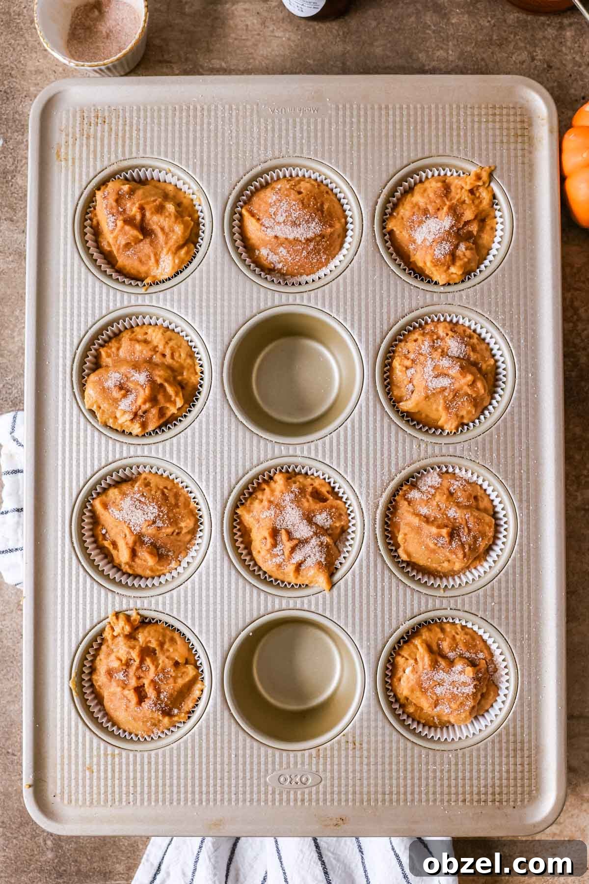 Overhead view of a muffin pan with sourdough pumpkin muffin batter inside before baking.