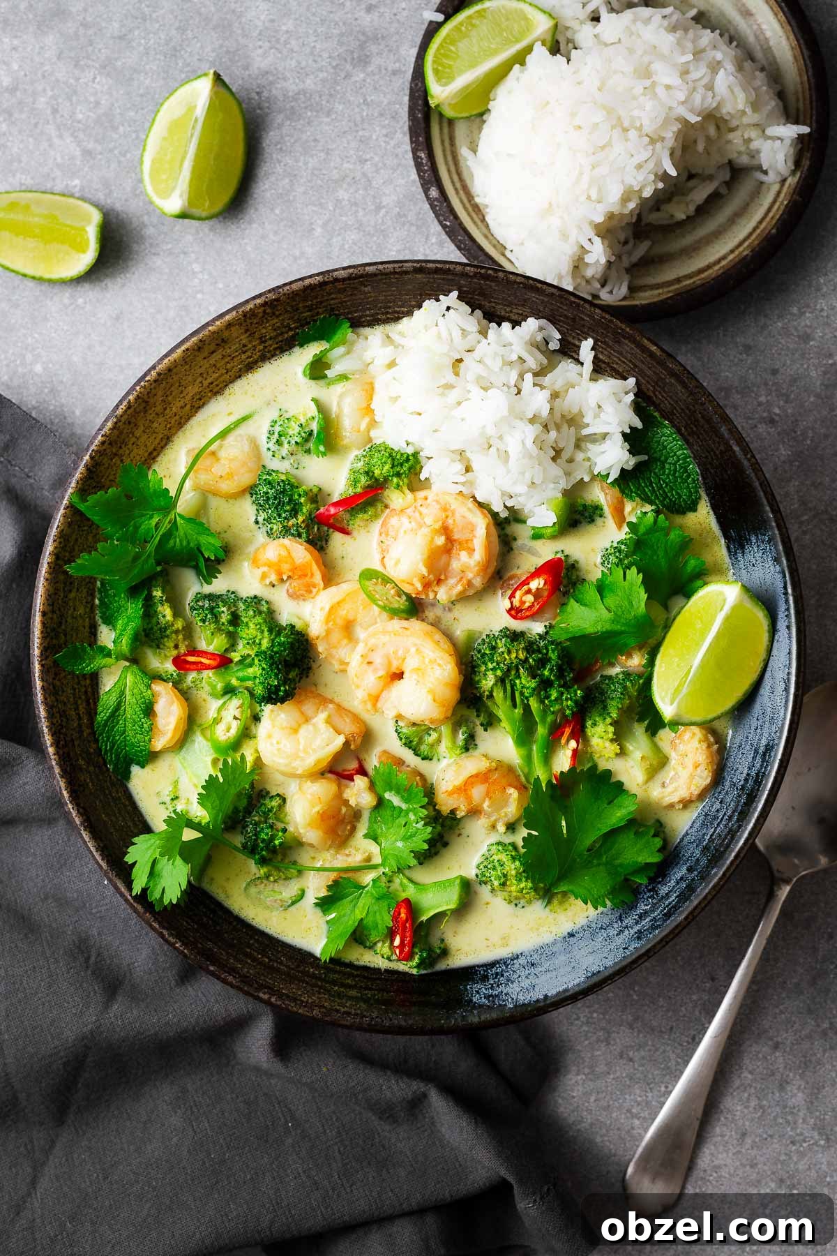 5 Ingredient Thai Green Curry Recipe 11 A five-ingredient Thai green curry with prawn tails and a side of rice, garnished with lime wedges and fresh herbs.