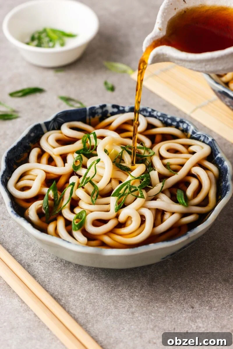 5 Ingredient Thai Green Curry Recipe 16 Pouring kake udon noodle broth over a Japanese bowl with udon noodles.