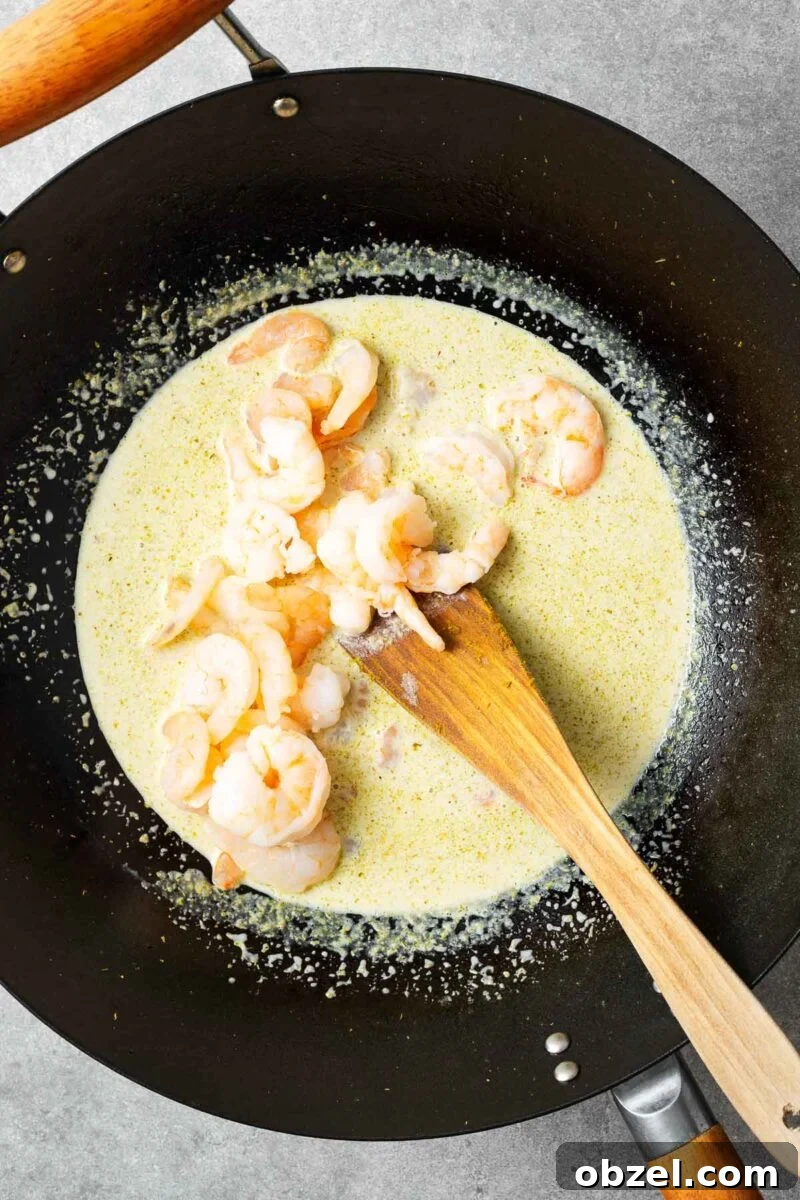 5 Ingredient Thai Green Curry Recipe 7 Shrimp added to a wok with green curry sauce.