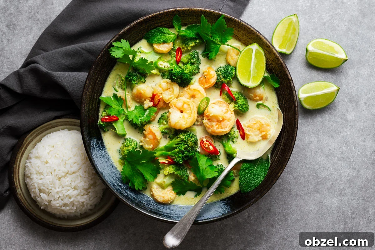 5 Ingredient Thai Green Curry Recipe 10 A Thai green curry bowl with shrimp and green vegetables garnished with fresh herbs and lime wedges with a serving spoon and a side or rice.