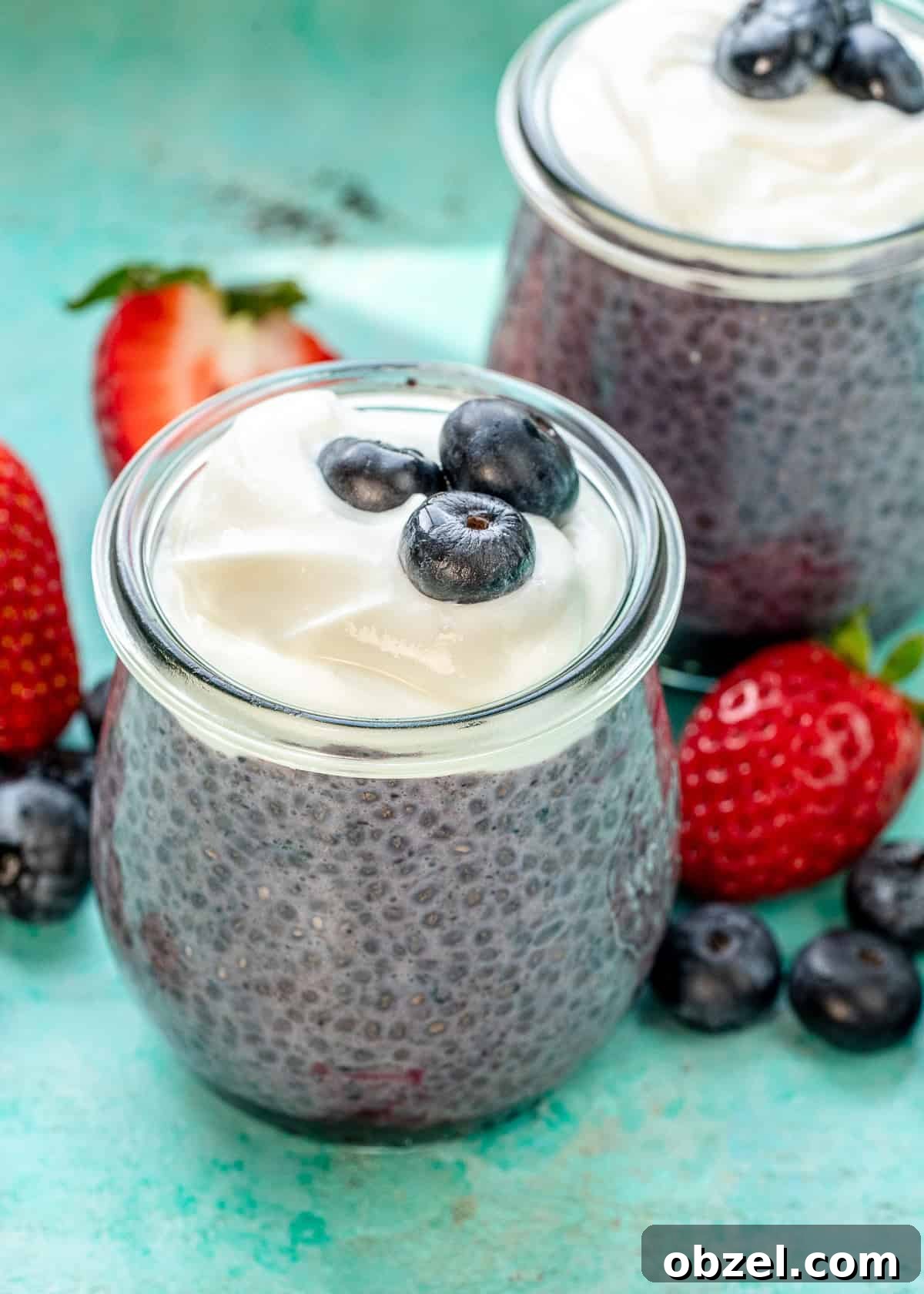 two chia blueberry pudding jars on a counter with berries
