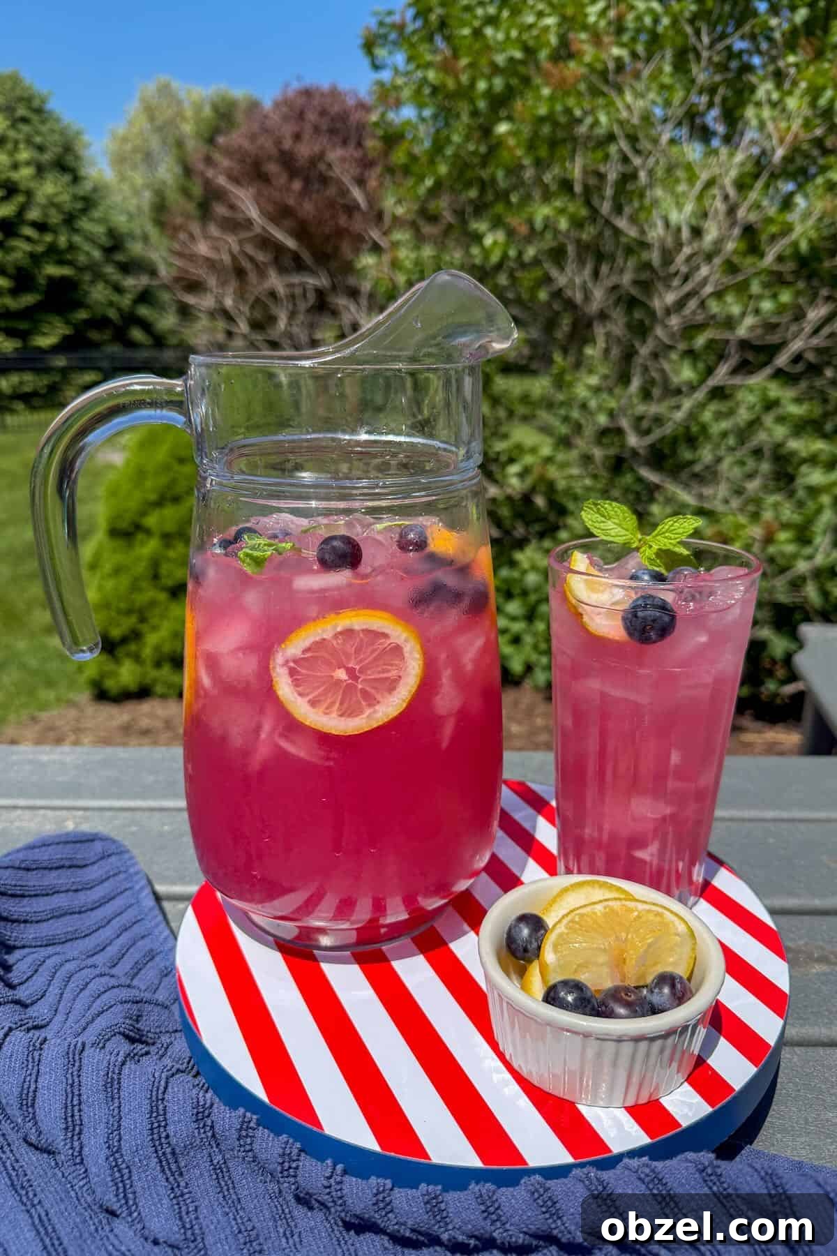 A red, white and blue tray with a glass pitcher of blueberry lemonade on the patio.