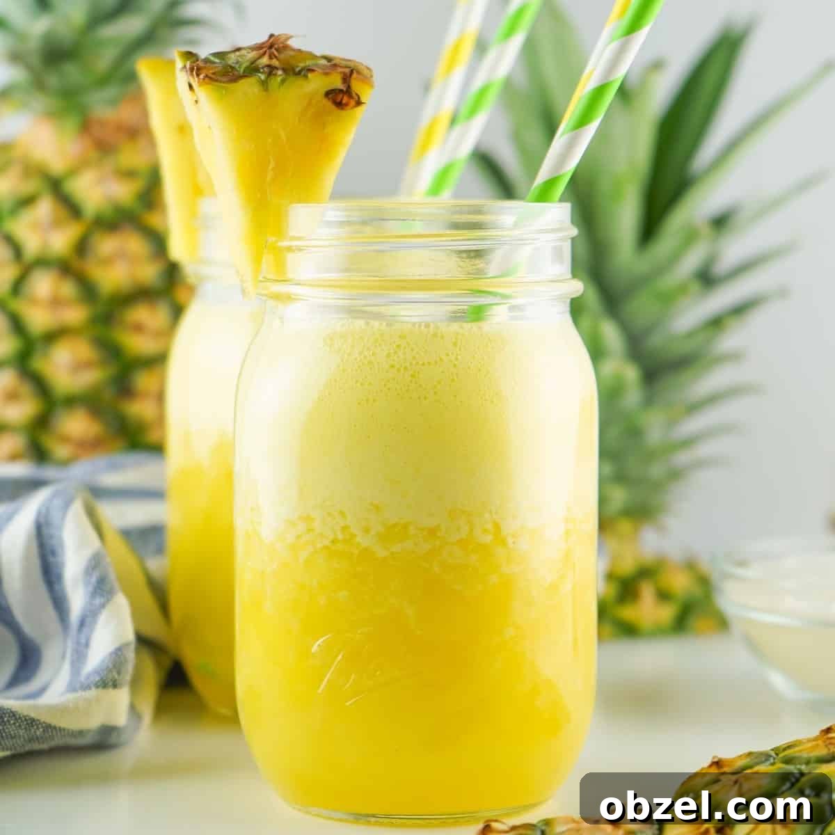 A mason jar filled with pineapple agua fresca and two straws.