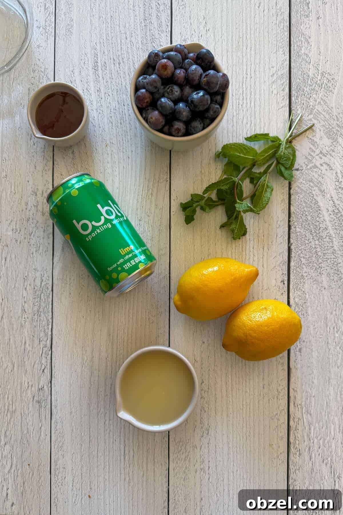 Ingredients to make blueberry lemonade with mint, honey, and bubbly water.