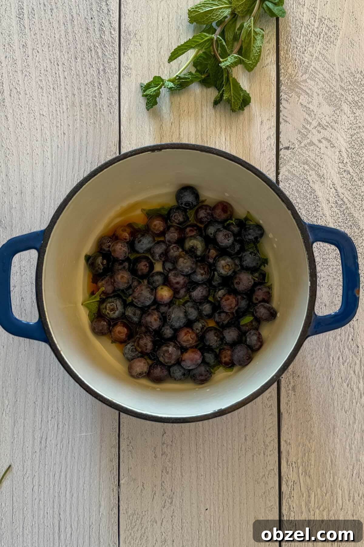 Blueberries, honey, water and crushed mint in a pan before simmering.