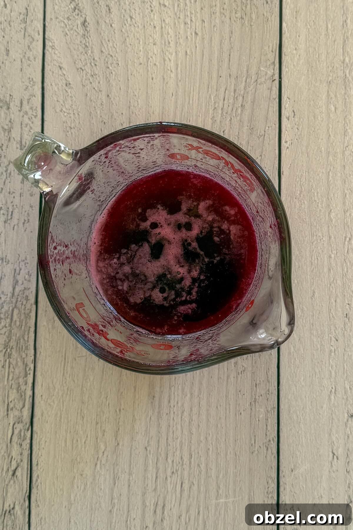 A measuring cup with blueberry simple syrup to cool.