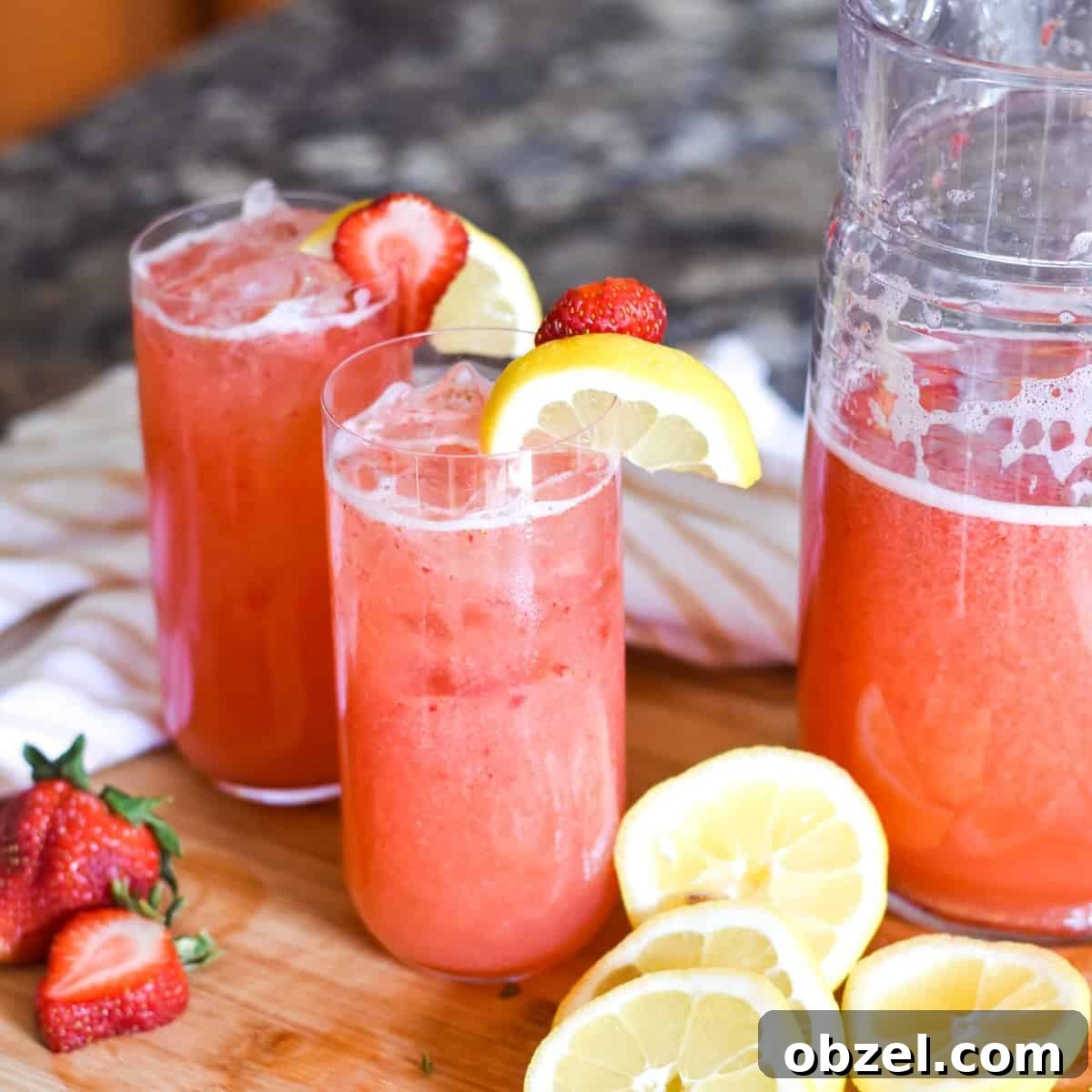 Glasses of strawberry lemonade topped with sliced fruit.