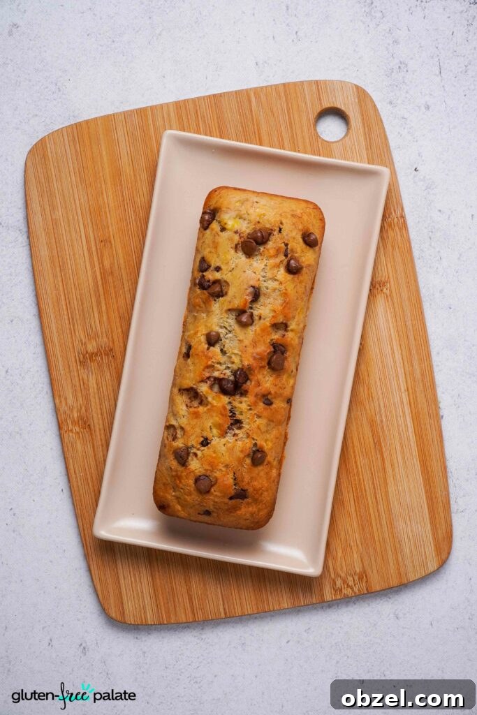 Moist Gluten-Free Banana Bread Recipe 8 Gluten-free banana bread on a white plate on a wooden bread board, ready to slice.
